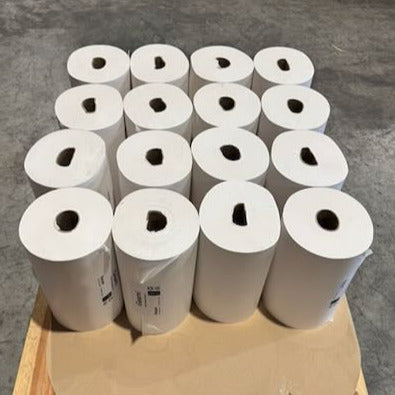 Multiple rolls of paper on a wooden pallet in an industrial setting